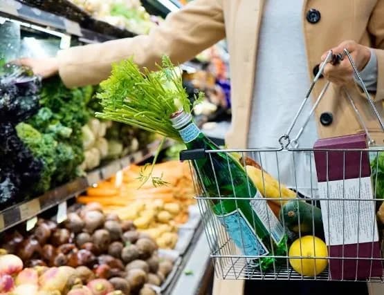 A shopper filling a basket from the fresh produce shelves